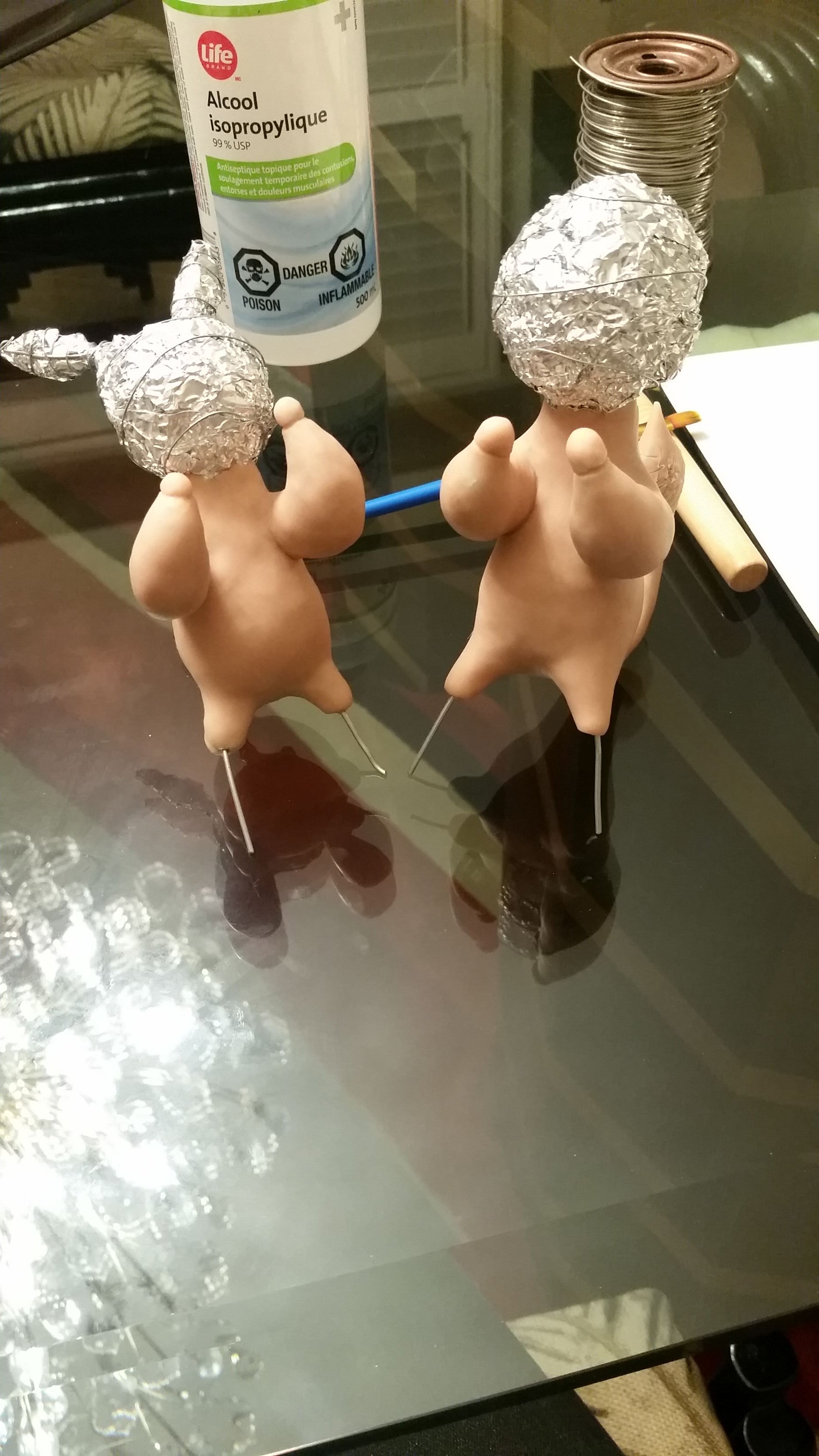 A work-in-progress photo, depicting the unpainted sculpts of the couple. The bodies are covered with sculpey and the heads are not yet completed. The heads are tinfoil balls wrapped in wires.