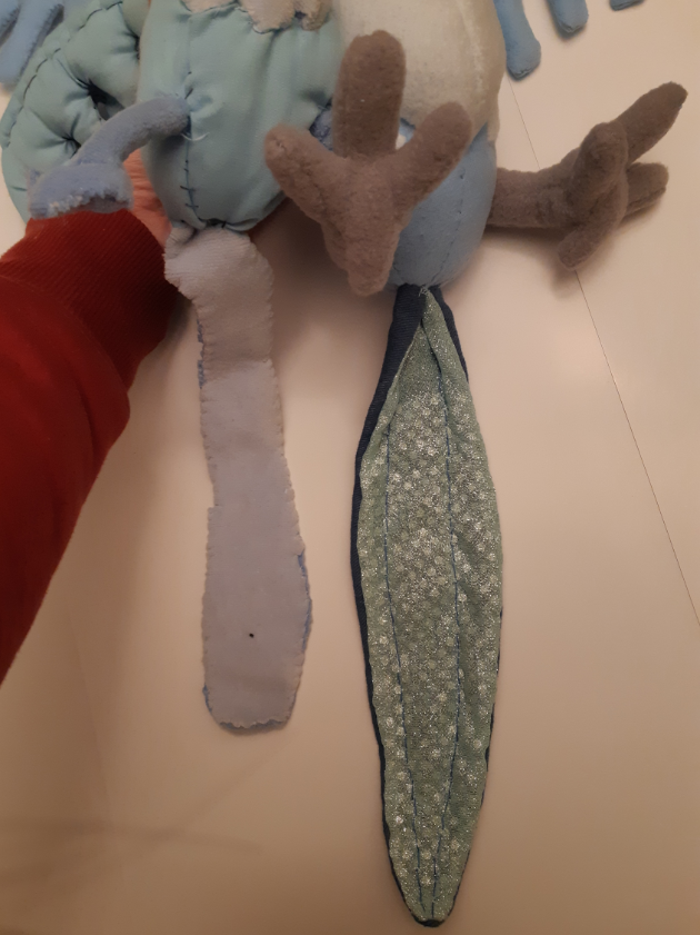 Side-by-side comparison of the two tail pieces, one looks like bacon, and the other looks like a banana peel with a glittery underside.