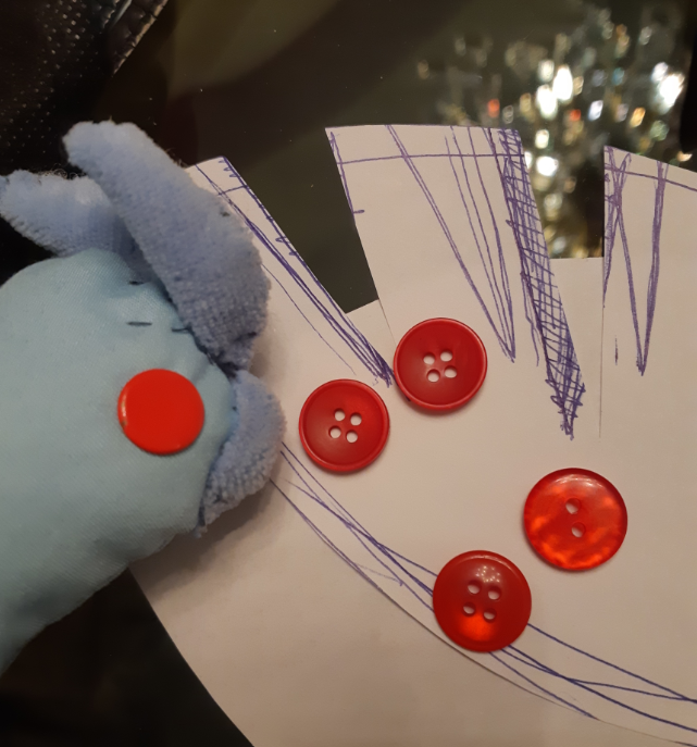 Close up of the old Articuno plush, next to two different sets of red buttons.