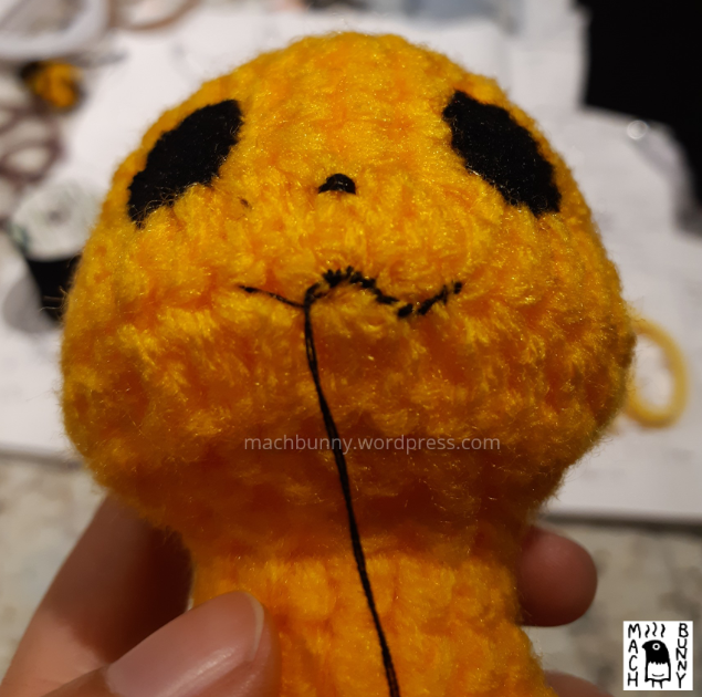 Amigurumi Detective Pikachu, front view of face with eyes, mouth, and nose stitched in place