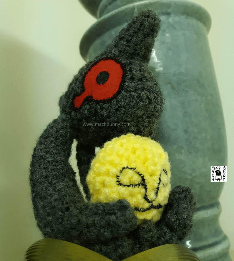 Amigurumi Yamask, front view from below, with arms holding mask