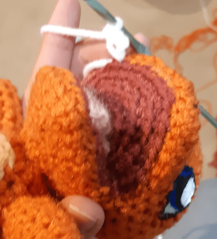 Amigurumi Charmander, with tooth being crocheted into place.