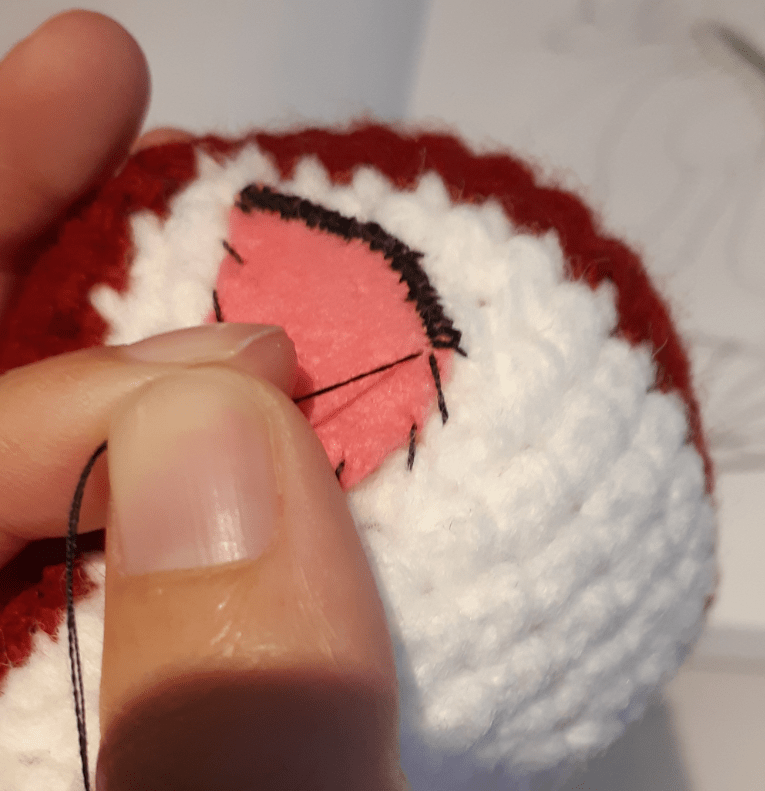 Amigurumi felt detailing : eye piece going through second round of stitching, pulling one stitch tight