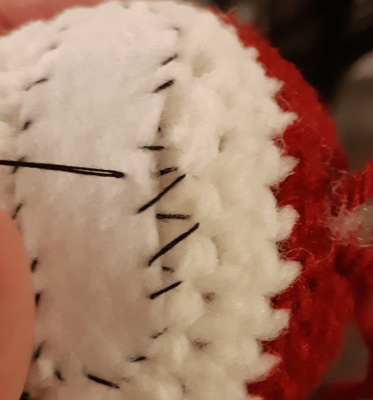 Amigurumi felt detailing : mouth piece roughly being stitched in place on the head