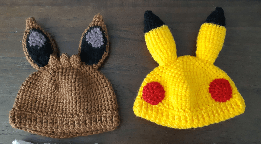 Pictures of the completed eevee and pikachu hats, showing the ears attached with added details, three tufts of hair on the eevee hat, and red cheeks on the pikachu hat.