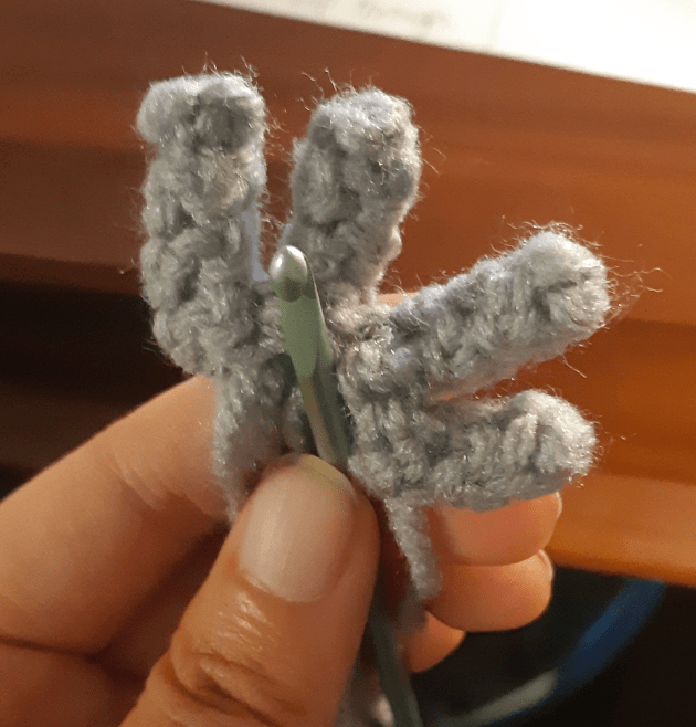 Four crocheted cylinders are being crocheted together at one end.