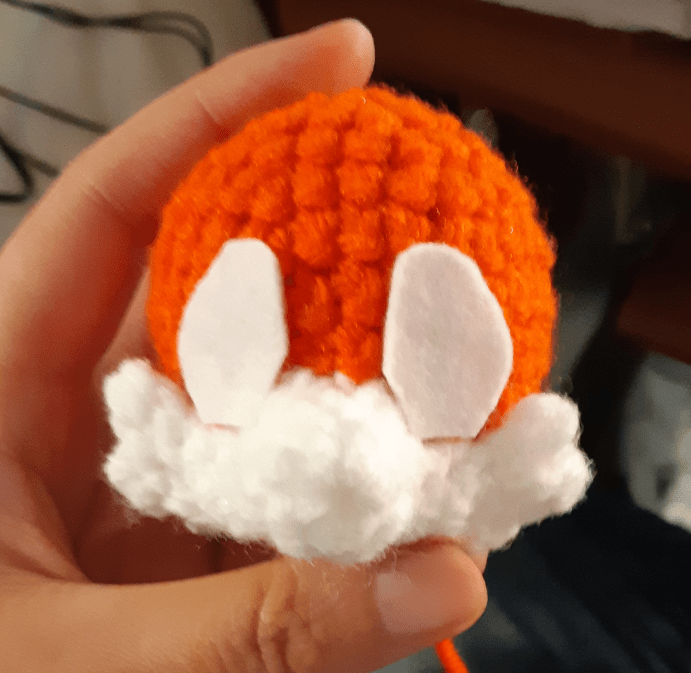 Image of the doll's head, with the muzzle piece stitched onto the head piece. Two felt eyes are placed onto the face, sitting just above the muzzle piece. 