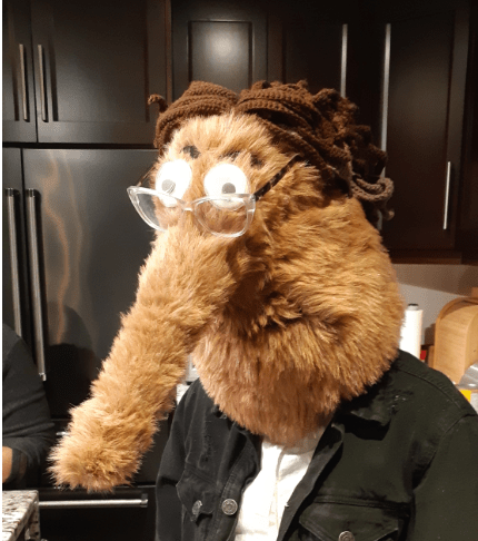 A mask resembling a worm on a string head, with added features such as glasses, crocheted brown hair, and eyebrows.